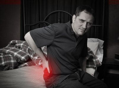 Man with Back Pain Sitting on Bed